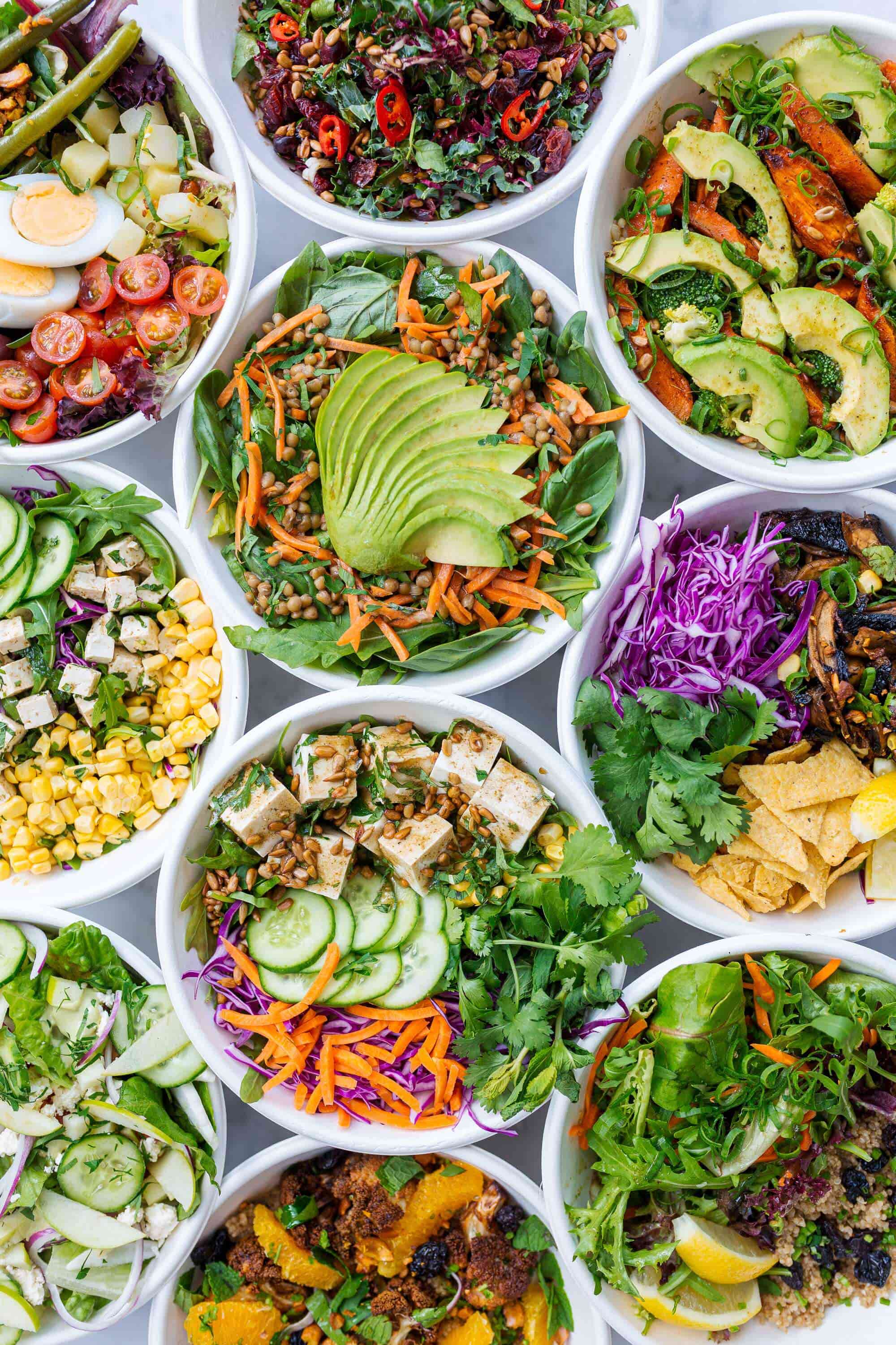 Several bowls of healthy meals, primarily salads and vegetarian