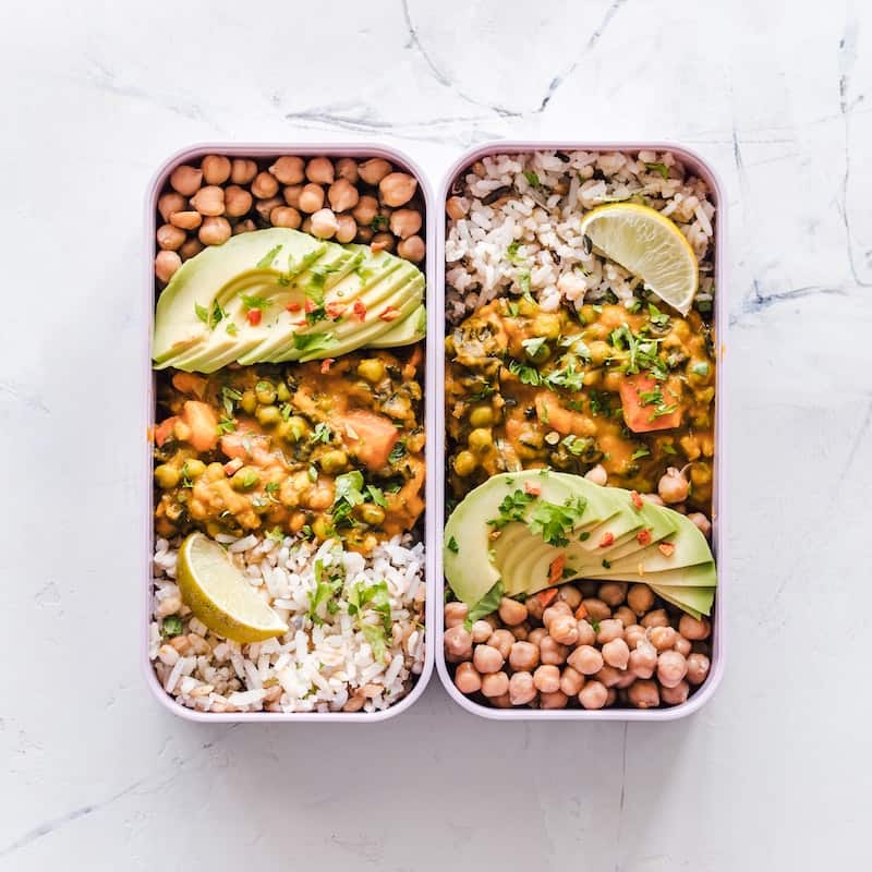 two containers filled with chicken, avocado, chickpeas and rice